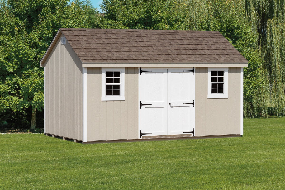Beige storage shed with white doors on a grassy area with trees in the background