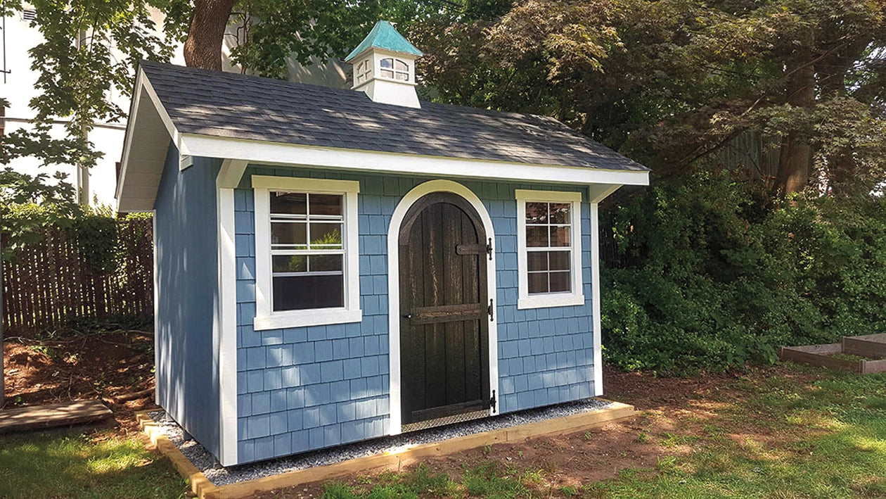 Small blue shed with a cupola in a garden setting