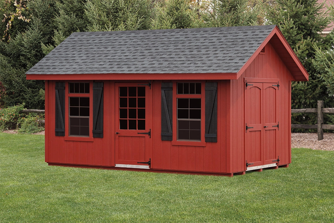 Red wooden shed with a gray roof on a grassy area