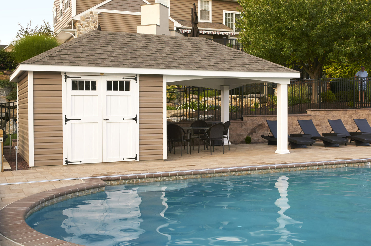 Pavilion next to a pool with lounge chairs and tables