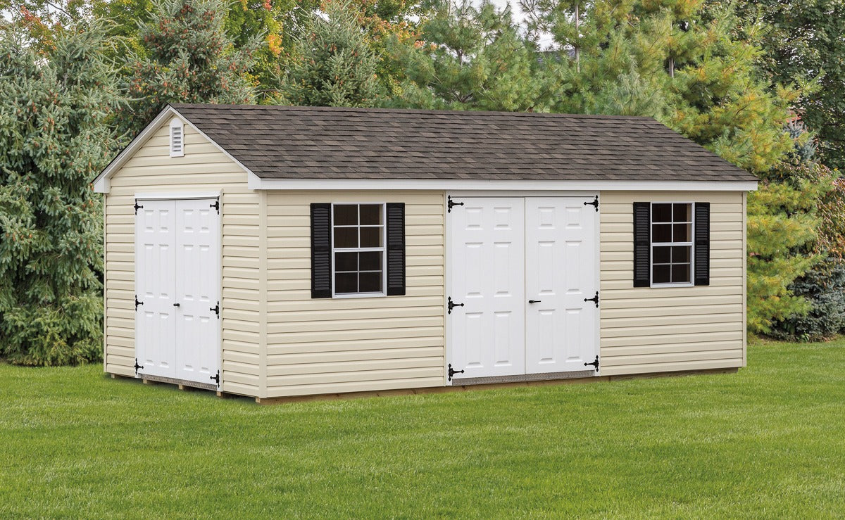 Storage shed with white doors and windows on a grassy area with trees in the background