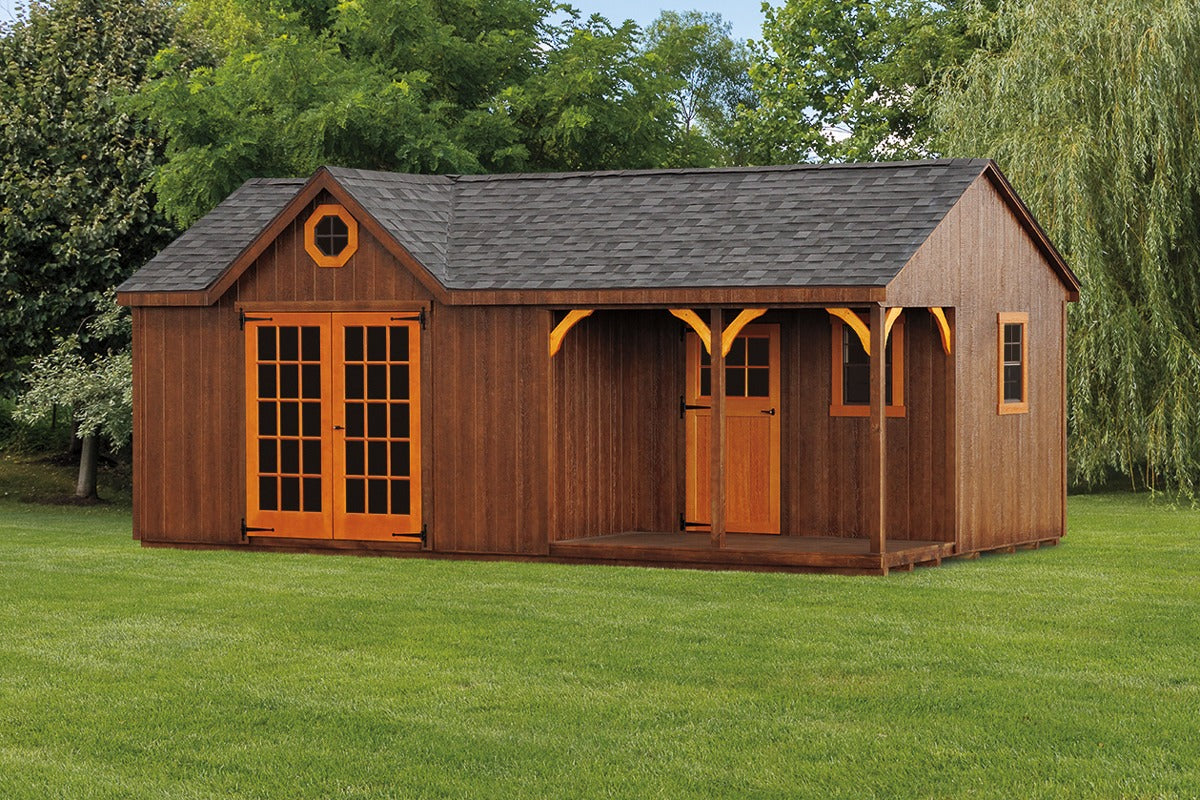 Wooden shed with brown exterior and orange trim on a grassy area with trees in the background