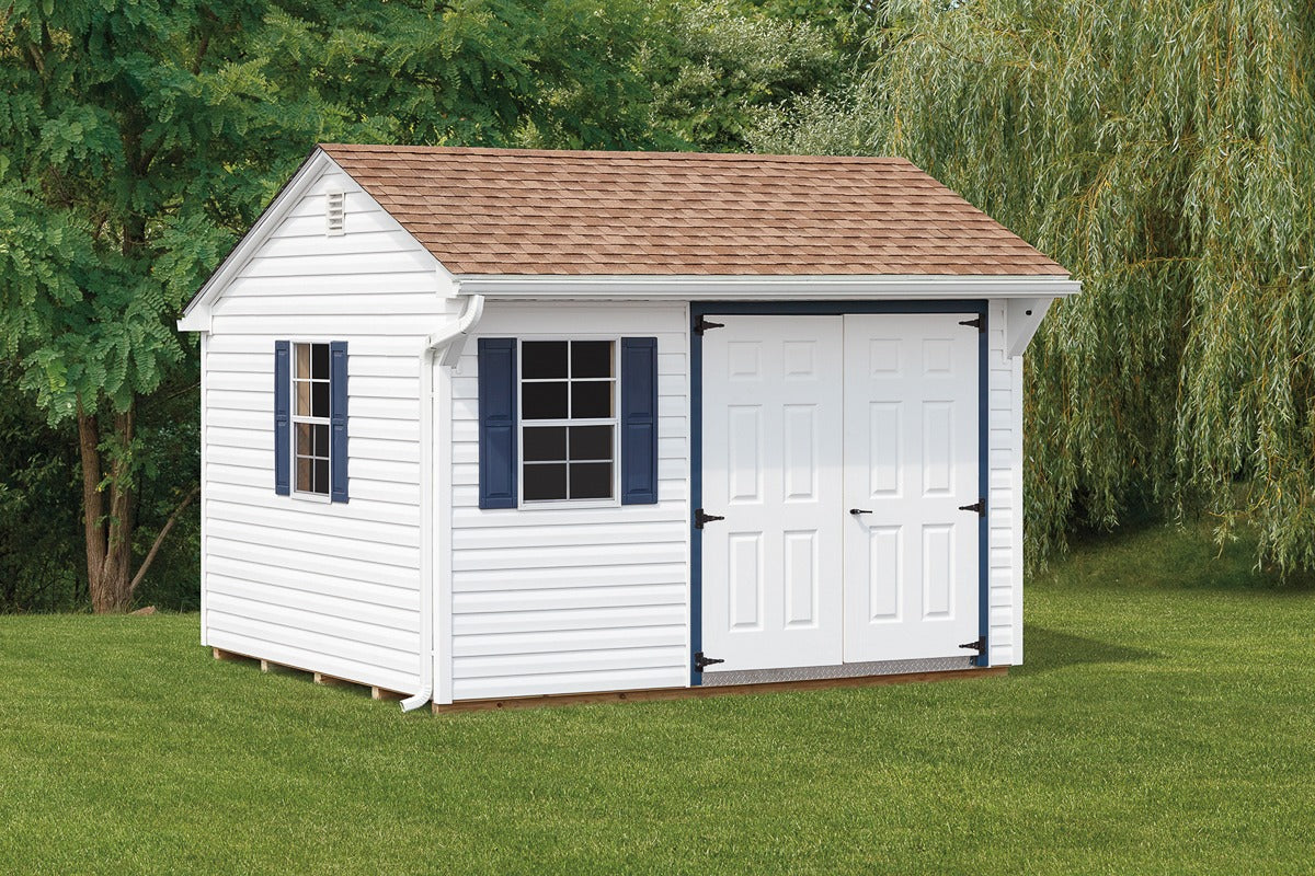 White storage shed with brown roof on a grassy area with trees in the background