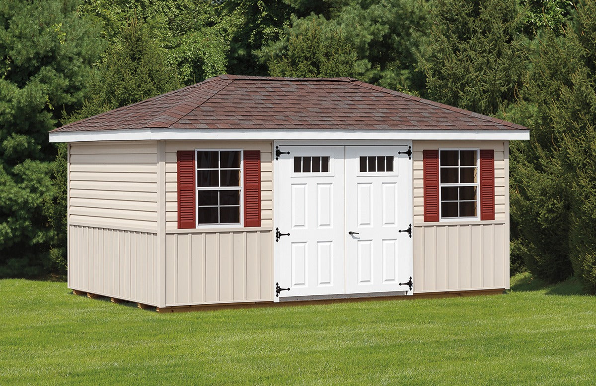 Storage shed with white doors and red shutters on a grassy area with trees in the background