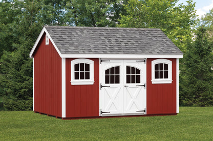 Red storage shed with white trim in a grassy area with trees