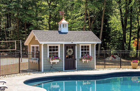 Small shed with a cupola next to a pool, surrounded by trees