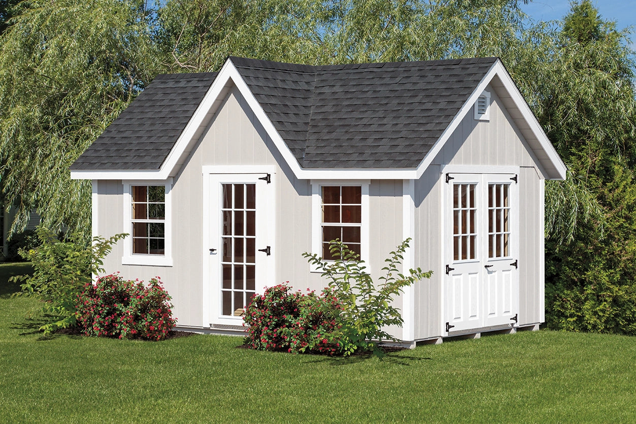 Small white house with gray roof in a garden setting