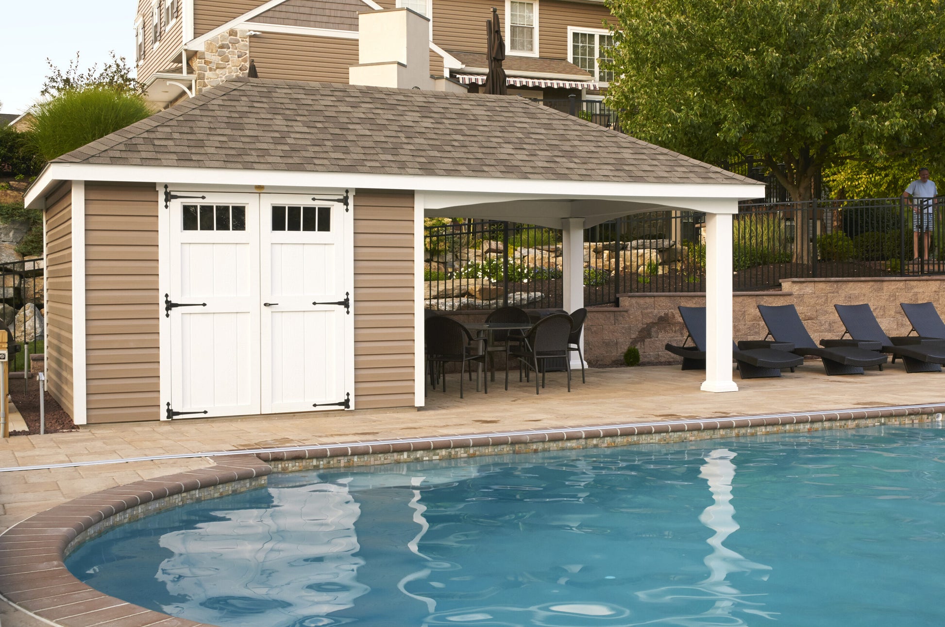Pavilion next to a pool with lounge chairs and tables