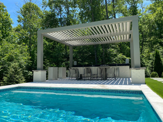 Pergola over a poolside area with chairs and tables, surrounded by trees.