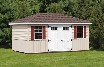 Storage shed with white doors and red shutters on a grassy area with trees in the background