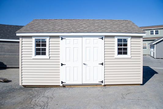 White storage shed with gray roof and windows on a clear day