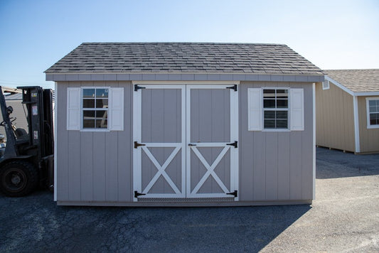 Gray storage shed with white doors and windows, parked outdoors with a forklift in the background.